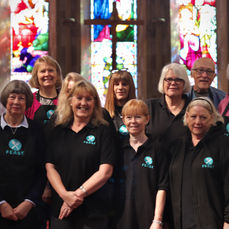 A group of FEAST volunteers in FEAST t shirts and aprons