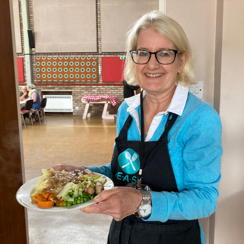 A FEAST volunteer carrying a roast lunch meal