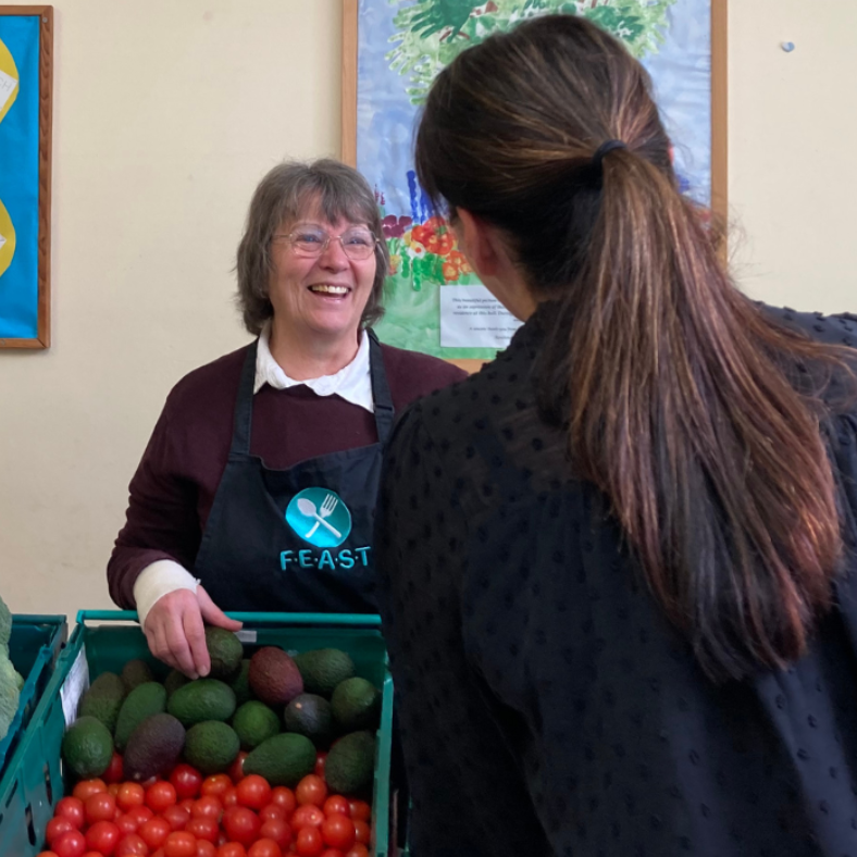 Feast larder guest being served by a smiling volunteer