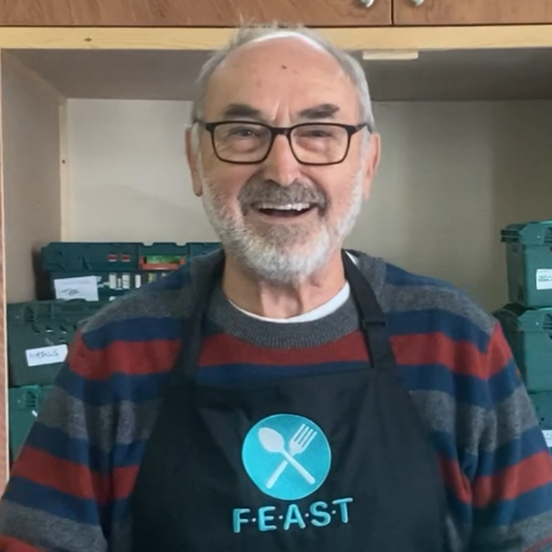 Feast male volunteer in logo apron smiling